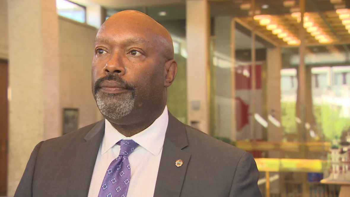 A photo of Markus Chambers looking off into the distance with the second floor of the council chambers building visible behind him