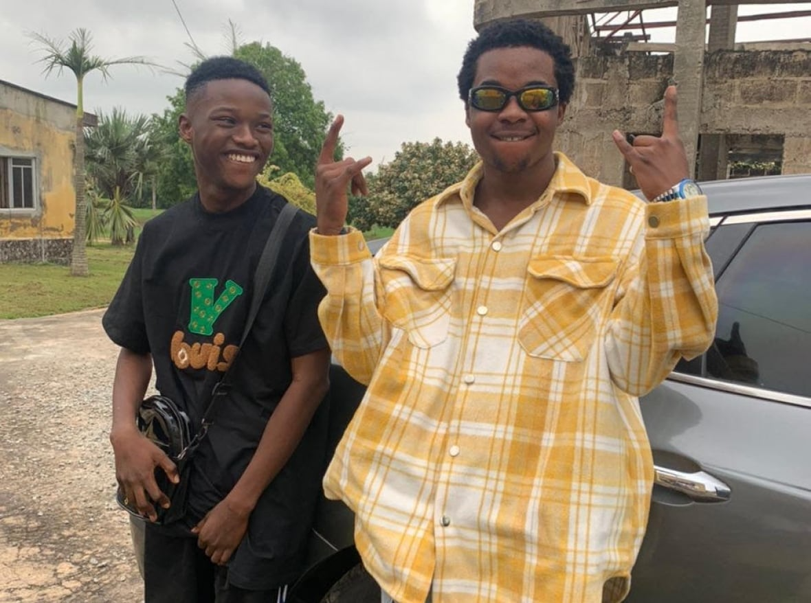 Photo of Afolabi wearing a yellow checkered shirt and sunglasses, standing next to his friend. They are both smiling.