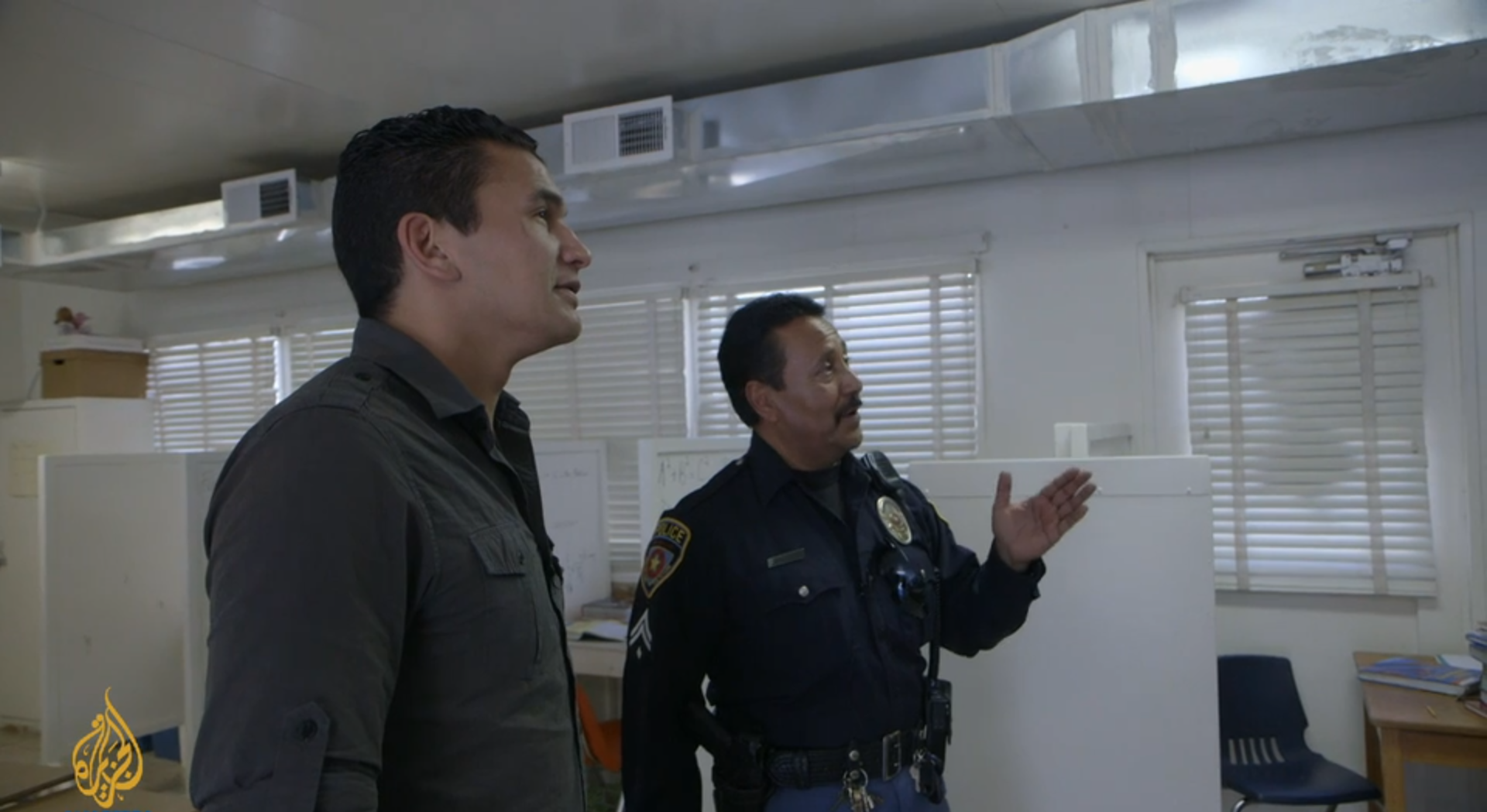 Kinew stands next to a police officer who is motioning to something off camera