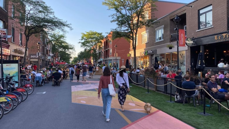 A car-free street in Montreal. There are many pedestrians and patios.