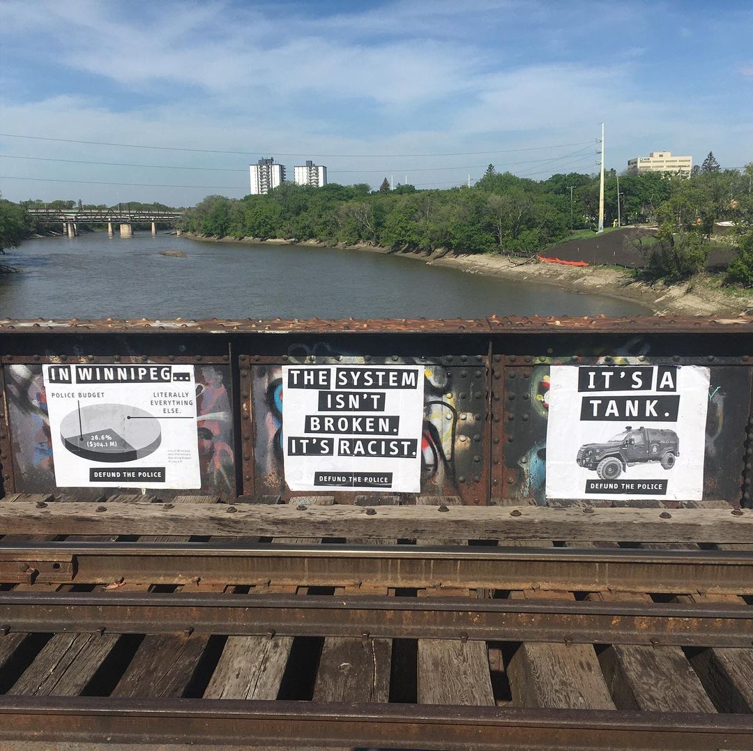 three police abolition posters on a bridge